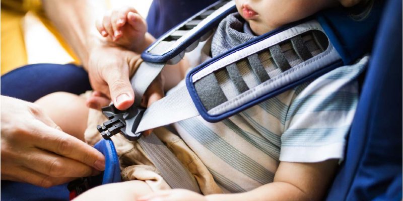 father-fastening-seat-belt-for-his-son-sitting-in